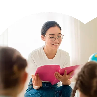 Educadora com um livro na mão e a ler às crianças, no âmbito do Curso de Auxiliar de Ensino Especial