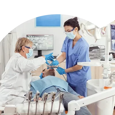 Dentista e assistente de clínica dentária a executarem uma cirurgia oral, após o Curso de Preparação e Apoio em Cirurgia Oral.