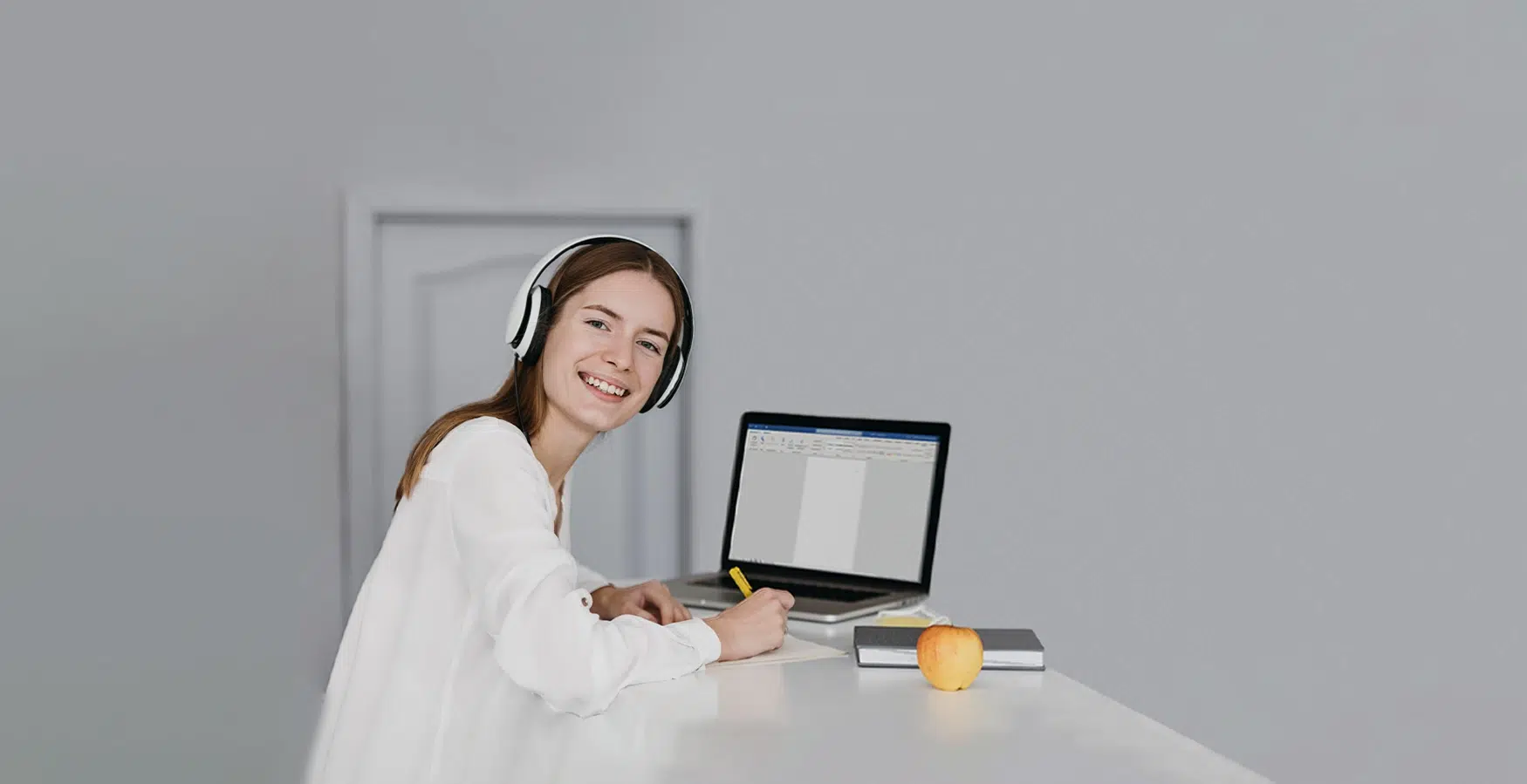 Rapariga de fones e de computador ligado a utilizar o Word, no âmbito do Curso Microsoft Word – Básico